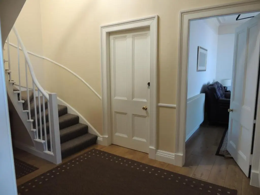 a hallway with a staircase with a door and a stair case at 5A Union Road in Macduff
