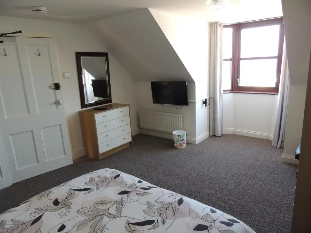 a bedroom with a bed and a dresser and a mirror at 5A Union Road in Macduff