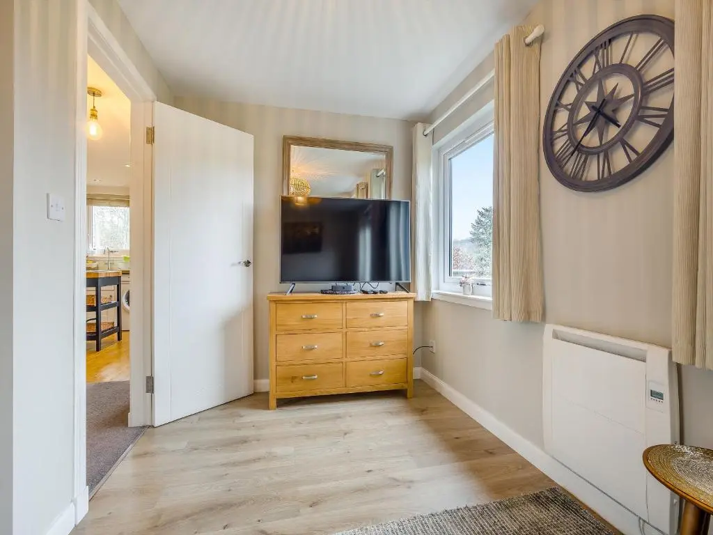 a living room with a television and a clock on the wall at Boreland Farm Cabin - Uk5855 in Kirkmichael