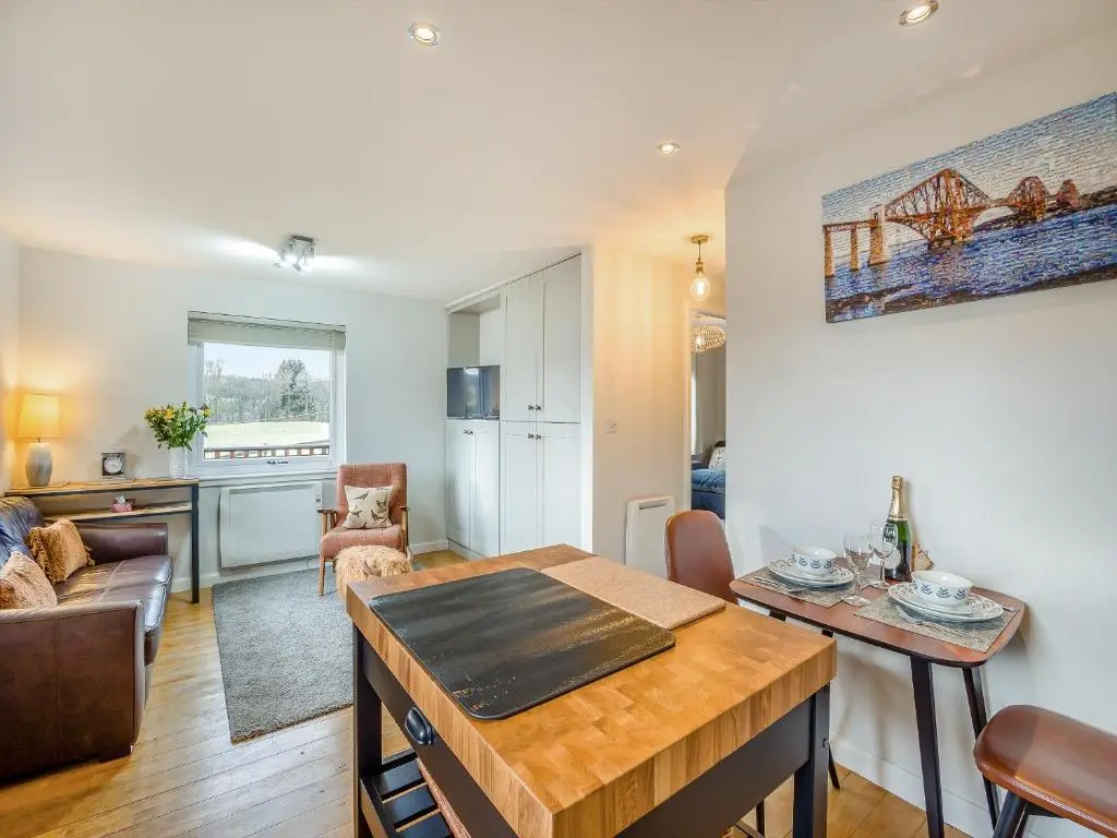 a living room with a table and a kitchen at Boreland Farm Cabin - Uk5855 in Kirkmichael