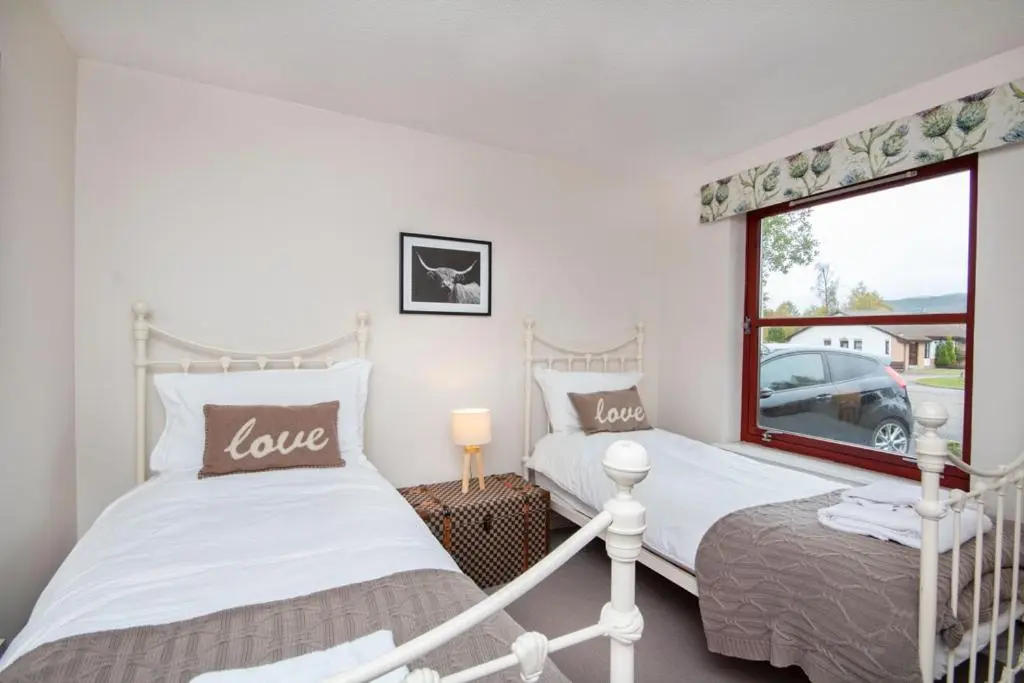 two twin beds in a room with a window at Aviemore Highlands No82 in Aviemore
