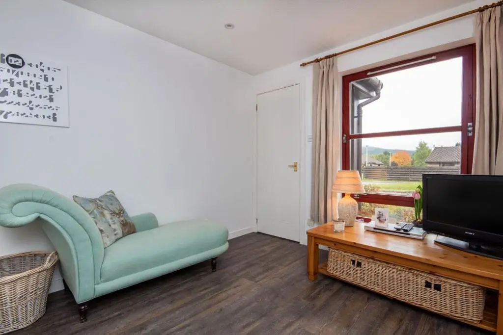 a living room with a blue chair and a television at Aviemore Highlands No82 in Aviemore