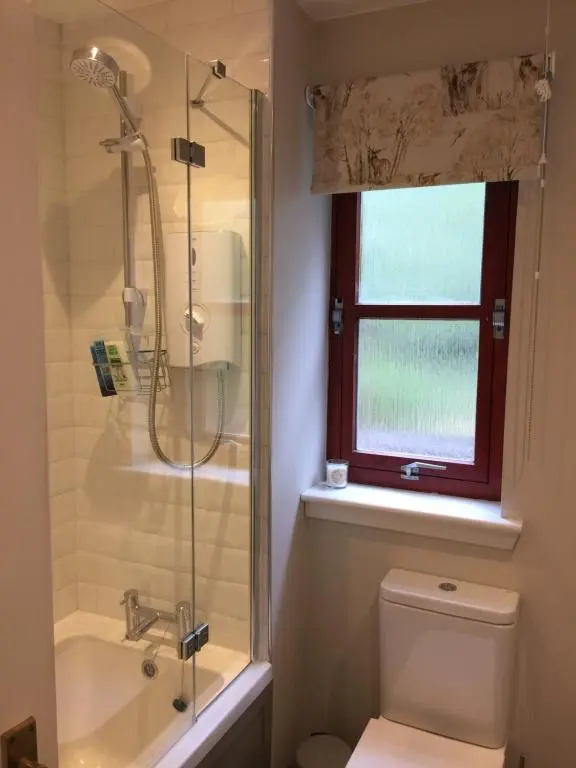 a bathroom with a shower and a toilet and a window at Aviemore Highlands No82 in Aviemore