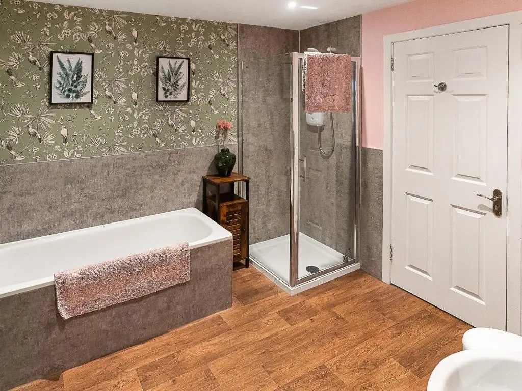 a bathroom with a bath tub and a shower at Garden Cottage in Tain