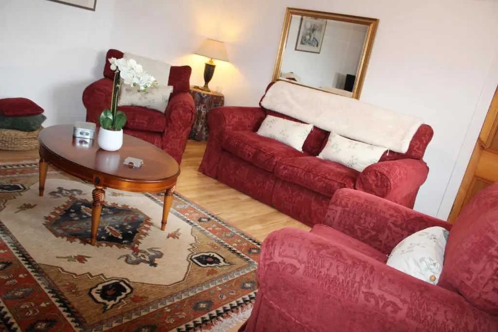 a living room with a red couch and a table at Ceol Na Mara Cottage by the sea in Nairn
