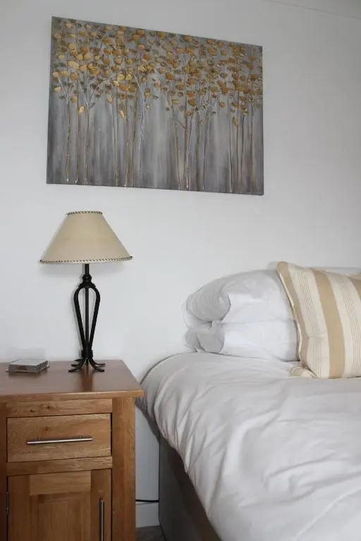 a bedroom with a bed and a table with a lamp at Ceol Na Mara Cottage by the sea in Nairn