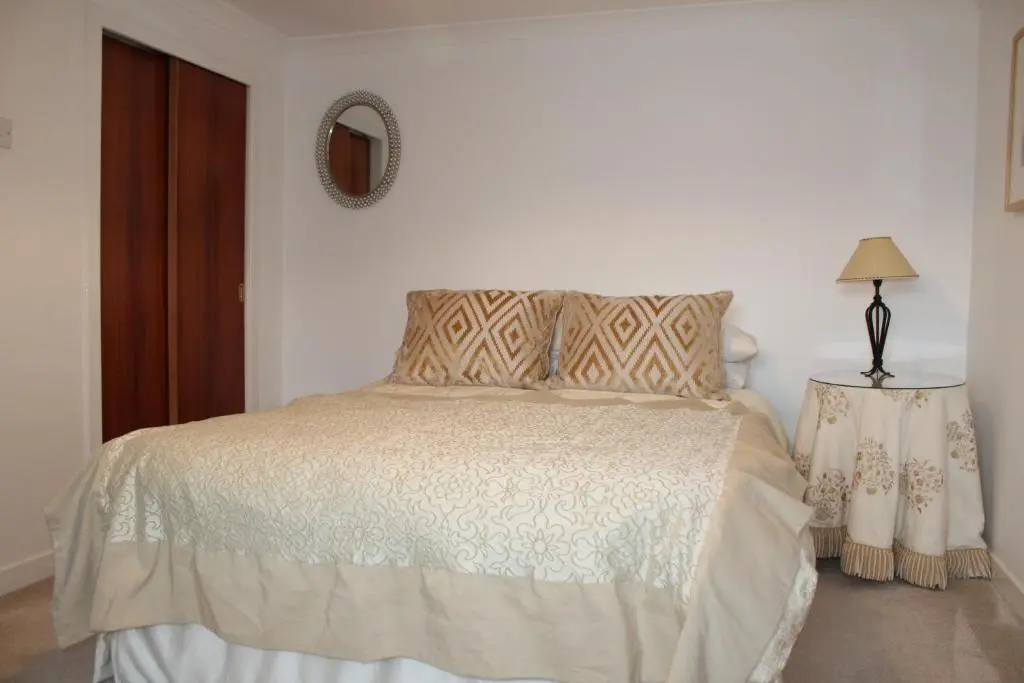 a bedroom with a bed and a table with a lamp at Ceol Na Mara Cottage by the sea in Nairn