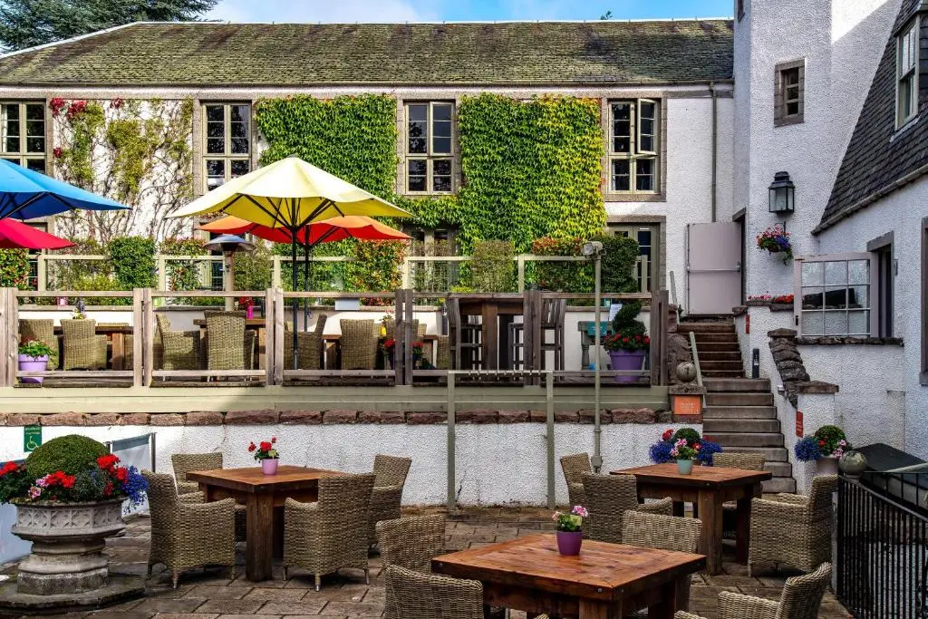 a patio with tables and umbrellas in front of a building at Banchory Lodge Hotel in Banchory