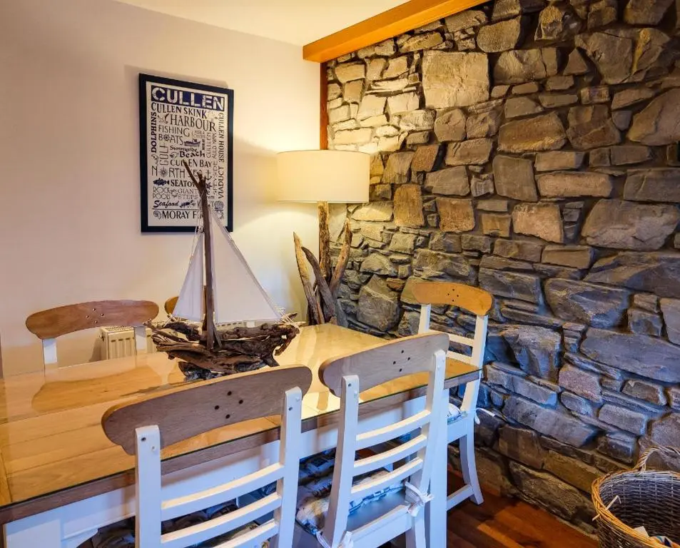 a dining room with a table and a stone wall at Cullen 117 Seatown With Sea Views in Cullen
