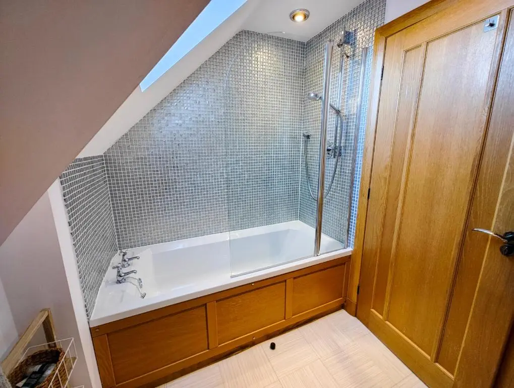 a bathroom with a tub and a shower with a glass door at Cullen 117 Seatown With Sea Views in Cullen