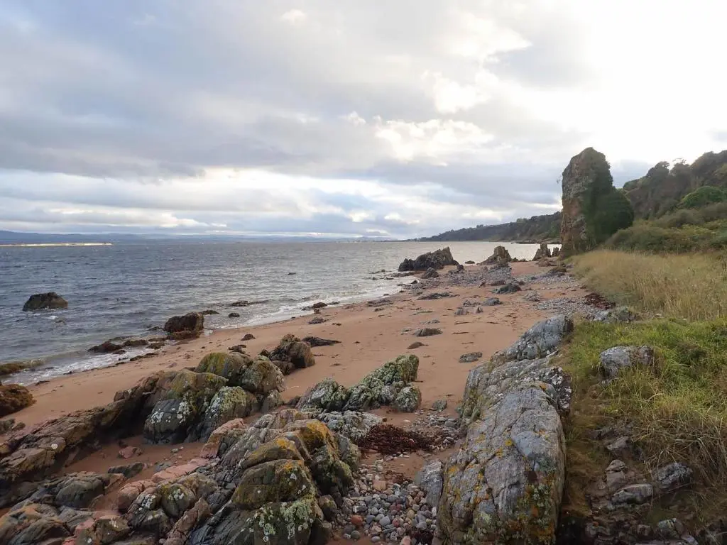 a beach with rocks and the ocean on a cloudy day at Dolphin View Hillockhead in Rosemarkie