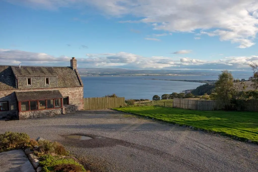 an old stone house with a view of the water at Dolphin View Hillockhead in Rosemarkie