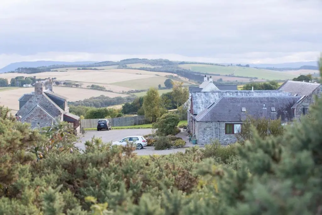 a stone house with a car parked in a parking lot at Dolphin View Hillockhead in Rosemarkie