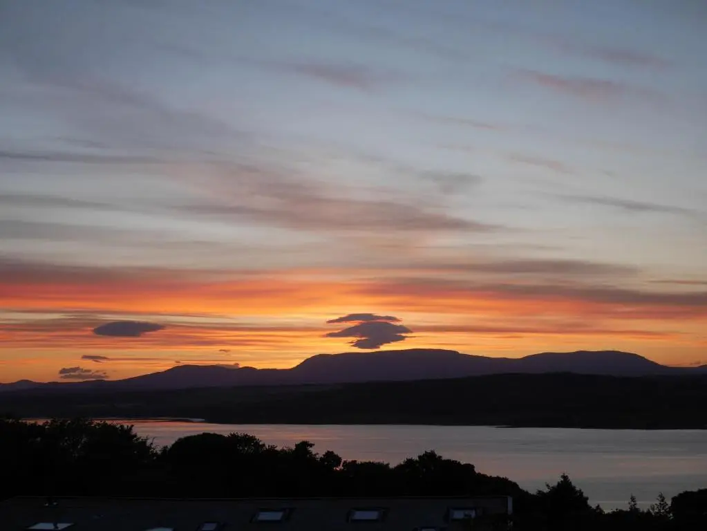 a sunset over a body of water with mountains at Wester Blackpark Farm in Inverness