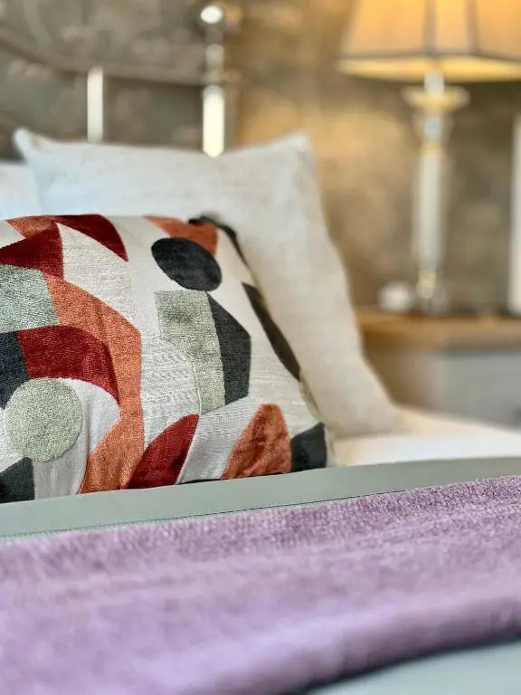 a close up of a bed with a colorful pillow at The Stags Head Apartment in Inverness