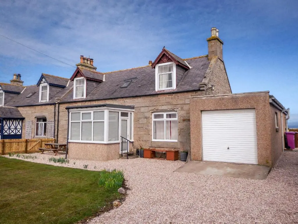 a large brick house with a white garage at The Mouries Holiday Cottage in Fochabers