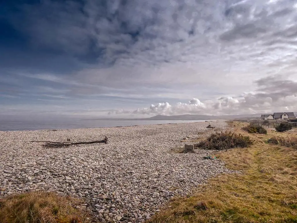 a rocky beach with a cloudy sky and the ocean at The Mouries Holiday Cottage in Fochabers