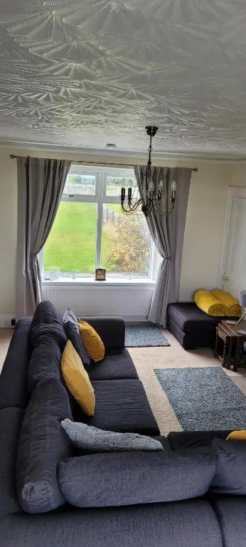 a living room with a couch and a window at The Mouries Holiday Cottage in Fochabers