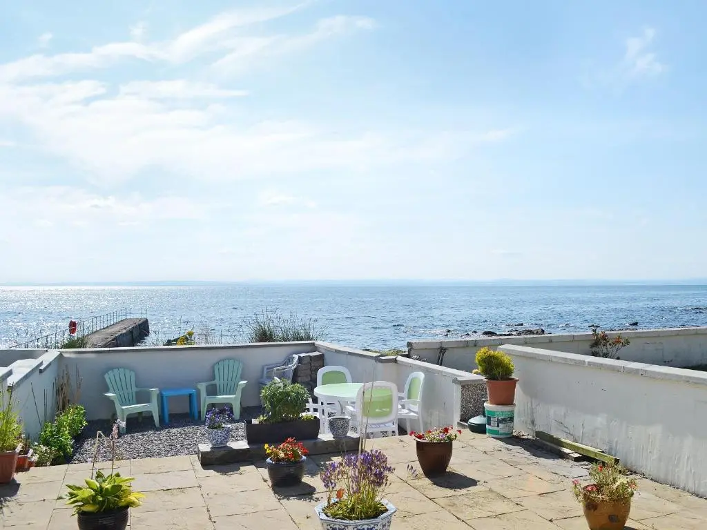 a patio with chairs and a view of the ocean at Seascape in Balintore