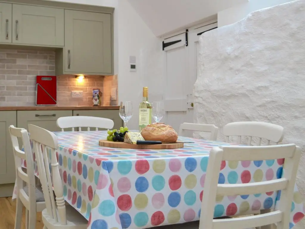 a table with a plate of food and a bottle of wine at Wester Laggan Cottage in Skye of Curr