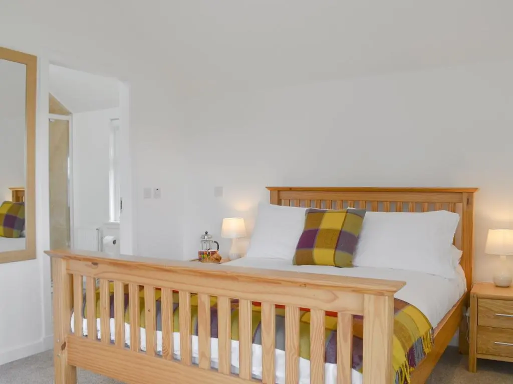 a bedroom with a wooden bed and a mirror at Wester Laggan Cottage in Skye of Curr