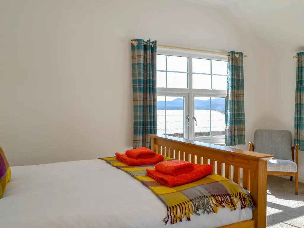 a bedroom with a bed and a desk and a window at Wester Laggan Cottage in Skye of Curr