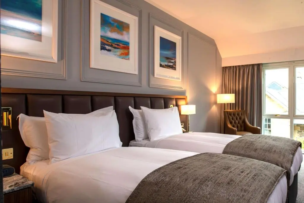 two beds in a hotel room with paintings on the wall at Ness Walk in Inverness