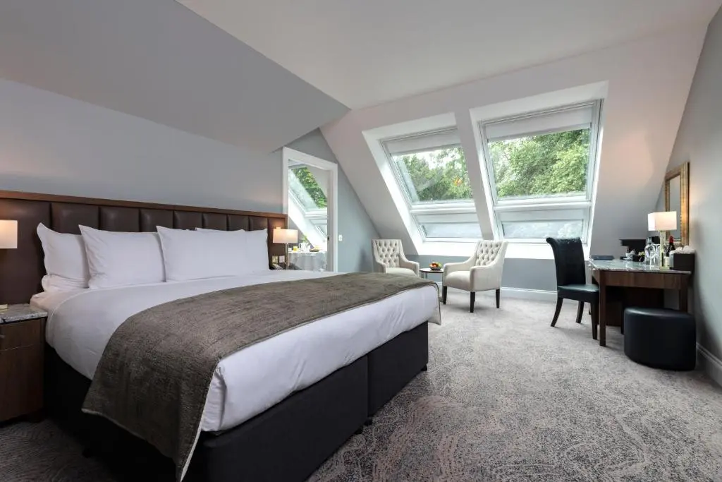 a bedroom with a large bed and a desk and chairs at Ness Walk in Inverness