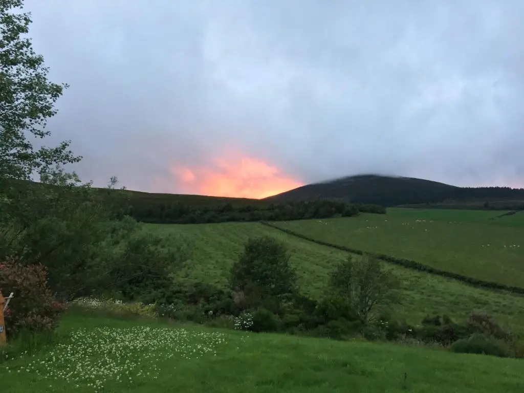 a field of green grass with a sunset in the background at The Gables Whisky B&B in Dufftown
