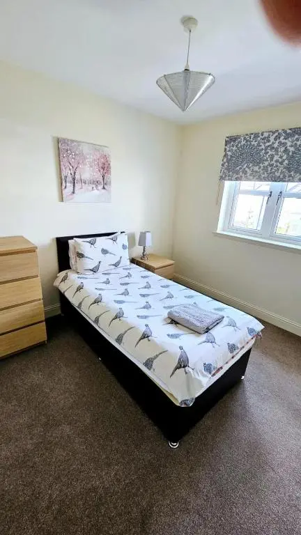a bedroom with a bed and a dresser and a window at 26 Woodgrove Drive in Inverness