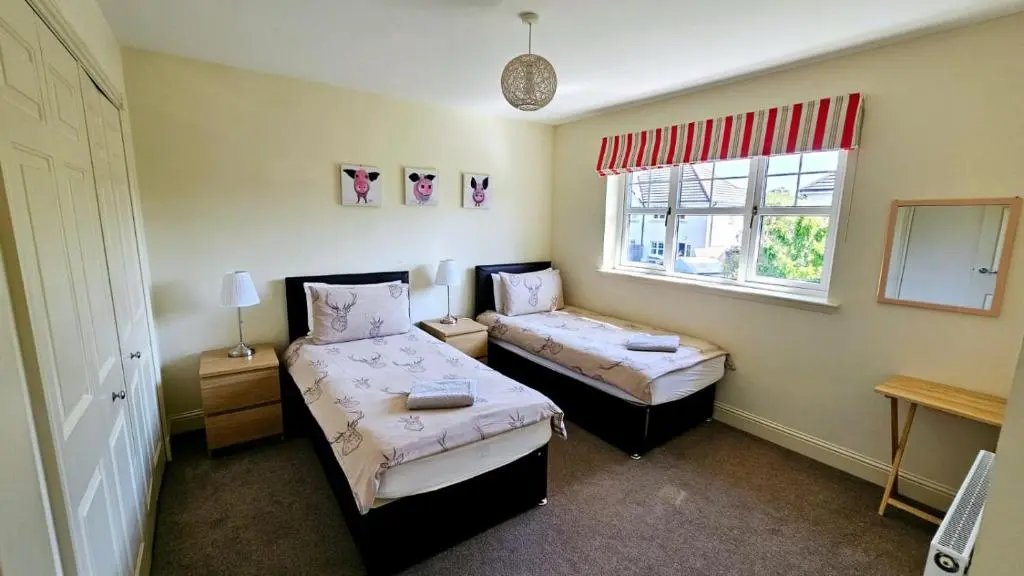 a small room with two beds and a window at 26 Woodgrove Drive in Inverness