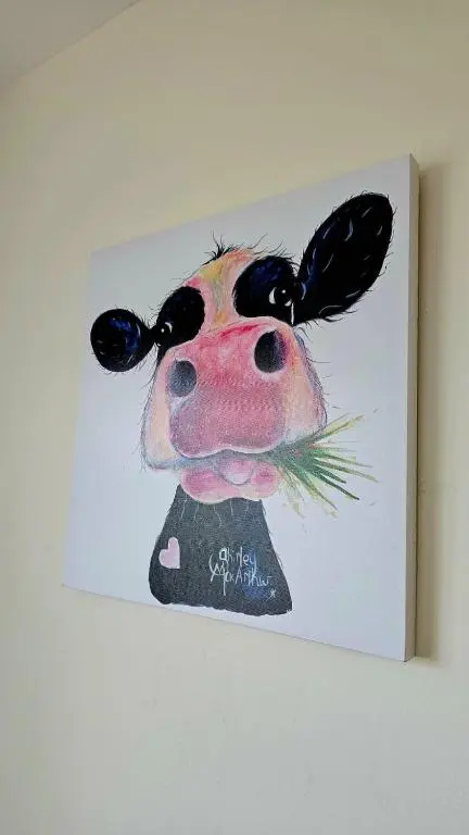 a painting of a cow hanging on a wall at 26 Woodgrove Drive in Inverness