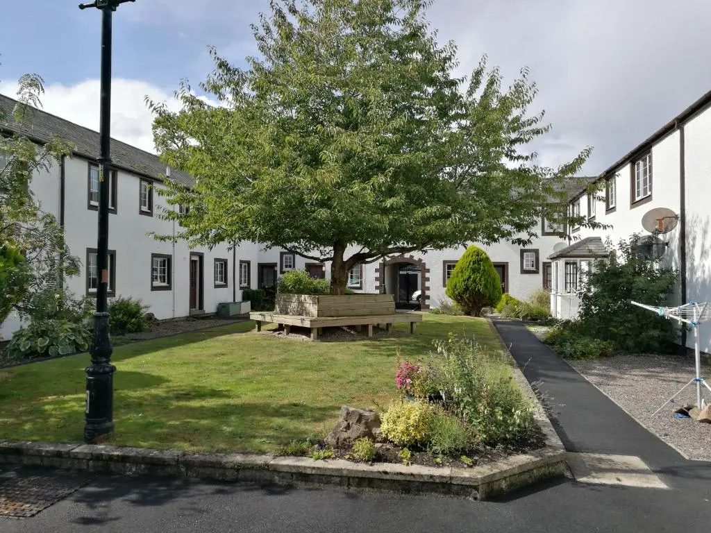 a park in front of a building with a tree and a bench at The Hedgehogs in Inverness