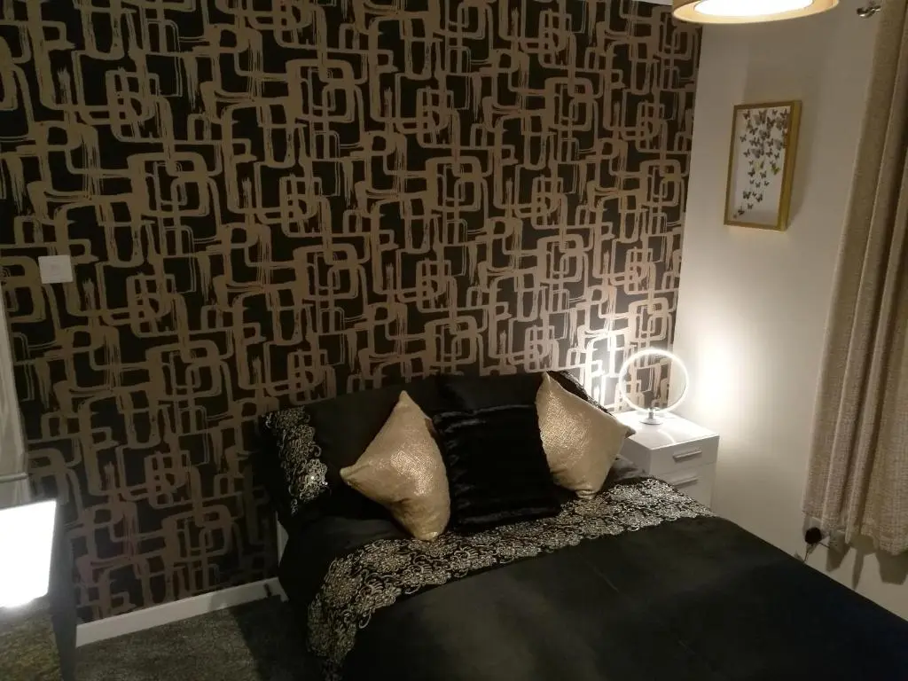 a bedroom with a black couch with a patterned wall at The Hedgehogs in Inverness