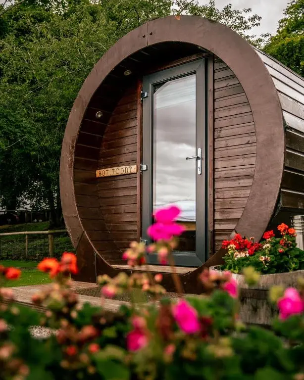 a circular building with a door and flowers in front of it at Delny Glamping and Farm Animals in Invergordon