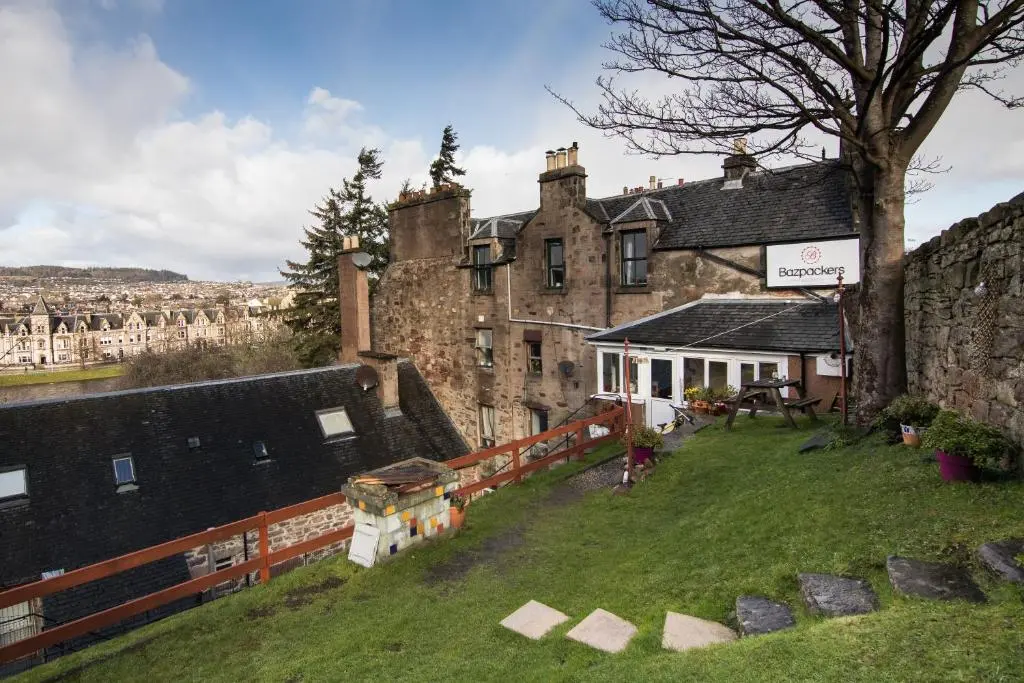 an old building with a grass yard in front of it at Bazpackers in Inverness