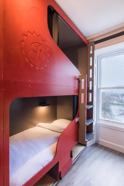 a red bunk bed in a room with a window at Bazpackers in Inverness