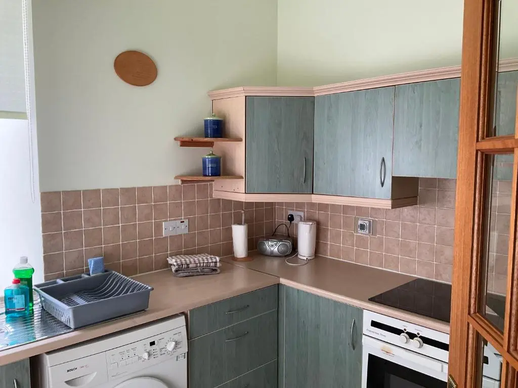 a kitchen with blue cabinets and a sink at Courtyard Cottage Free Parking in Inverness