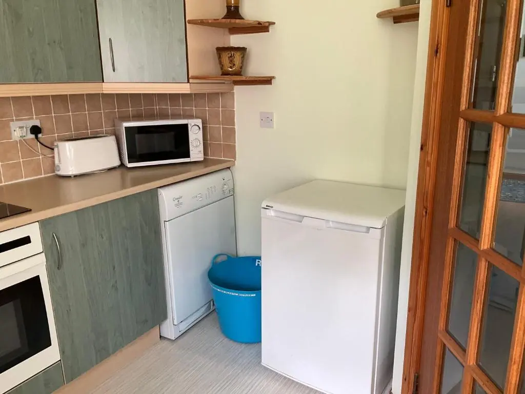 a small kitchen with a refrigerator and a microwave at Courtyard Cottage Free Parking in Inverness