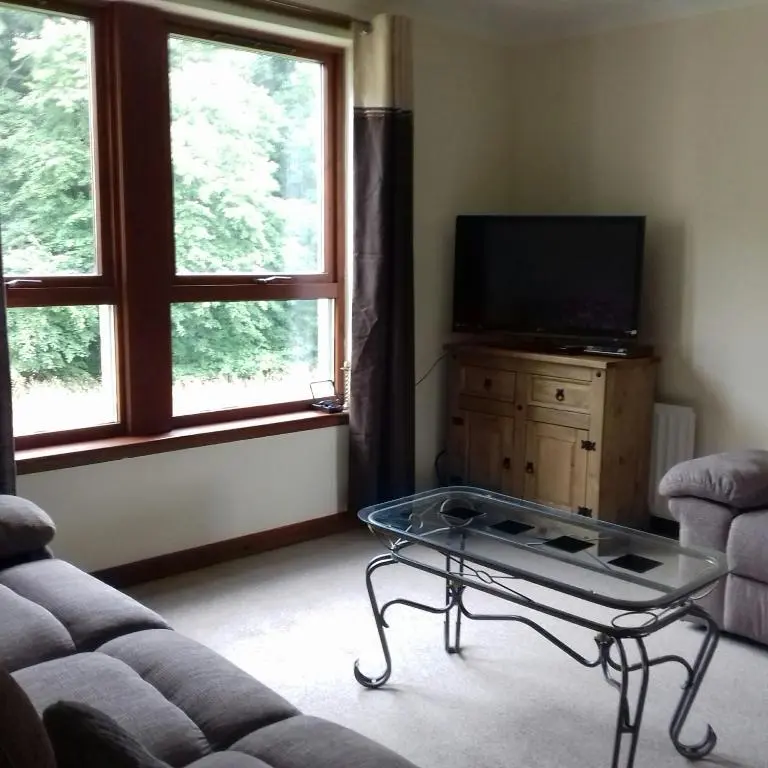 a living room with a couch and a glass coffee table at Culduthel Vista Apartment in Inverness