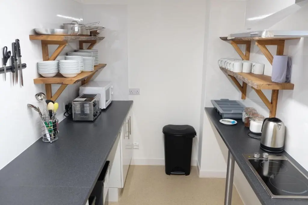 a kitchen with a counter with dishes on shelves at Black Isle Hostel in Inverness