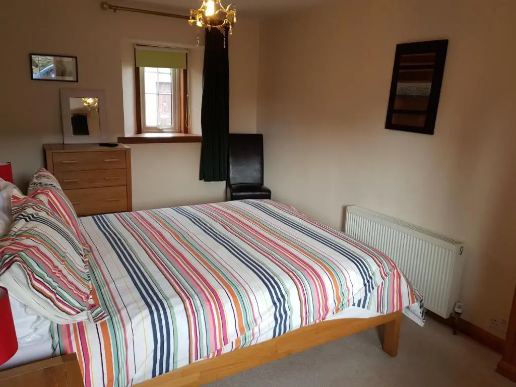 a bedroom with a bed with a colorful striped comforter at 6 Seatown, Lossiemouth in Lossiemouth