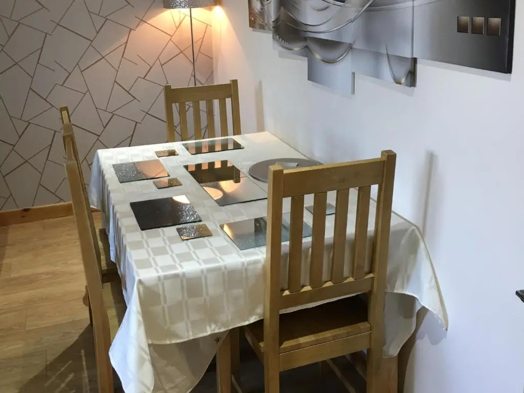 a table with two chairs and a white table cloth on it at Azim and Suzi\u2019s city centre apartment Inverness in Inverness