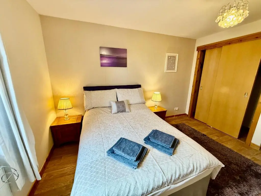 a bedroom with a bed with two blue towels on it at Azim and Suzi\u2019s city centre apartment Inverness in Inverness