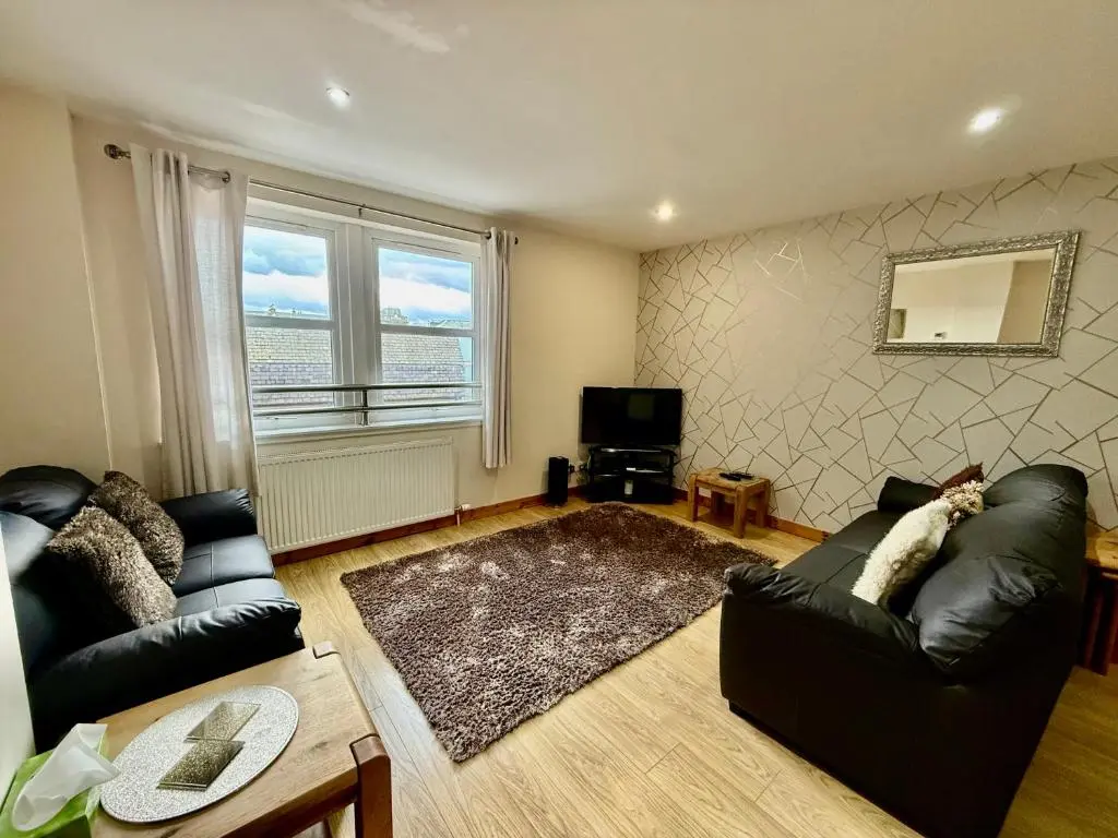 a living room with a black leather couch and a television at Azim and Suzi\u2019s city centre apartment Inverness in Inverness