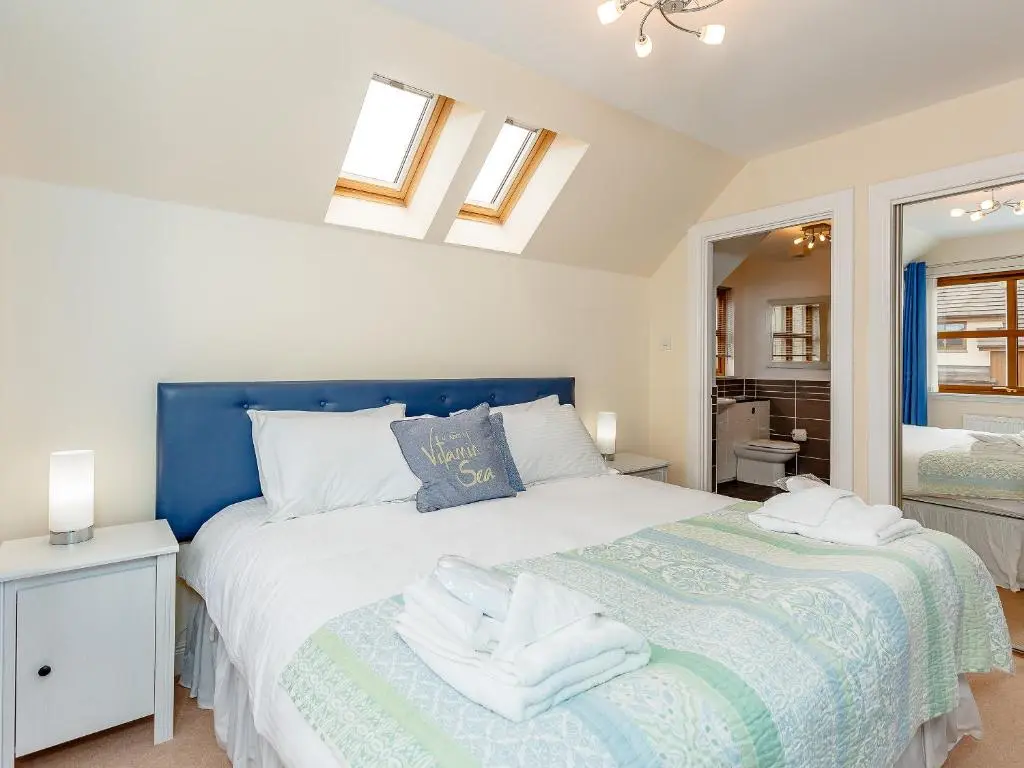 a bedroom with a blue and white bed and a mirror at The Lookout in Aviemore