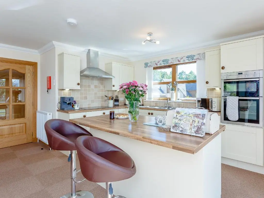 a kitchen with a counter with two chairs and a vase of flowers at The Lookout in Aviemore