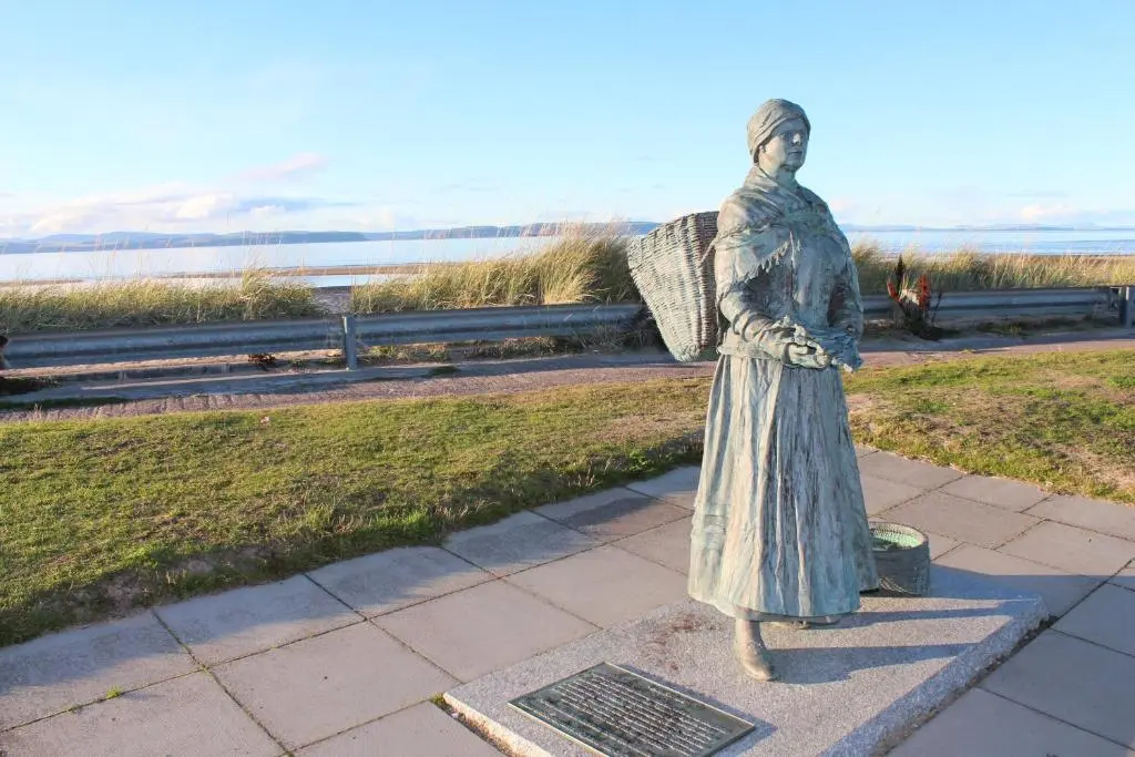 a statue of a woman standing on a sidewalk at Douglas House Apartments in Nairn