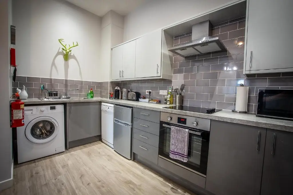 a large kitchen with a washer and dryer in it at Douglas House Apartments in Nairn
