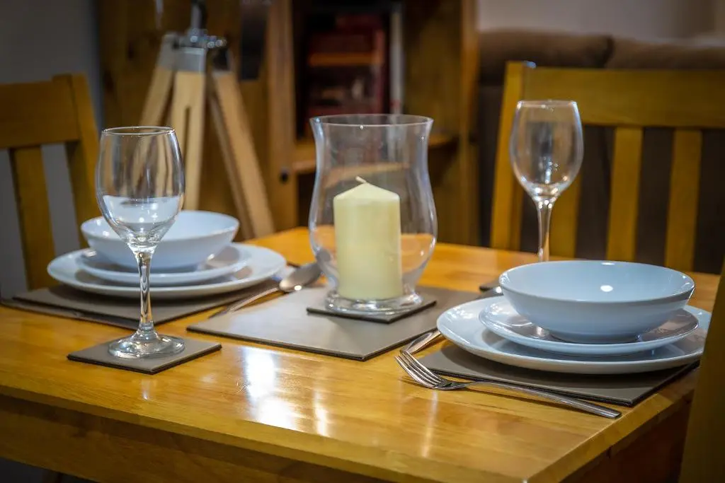 a wooden table with a candle and plates and glasses at Douglas House Apartments in Nairn